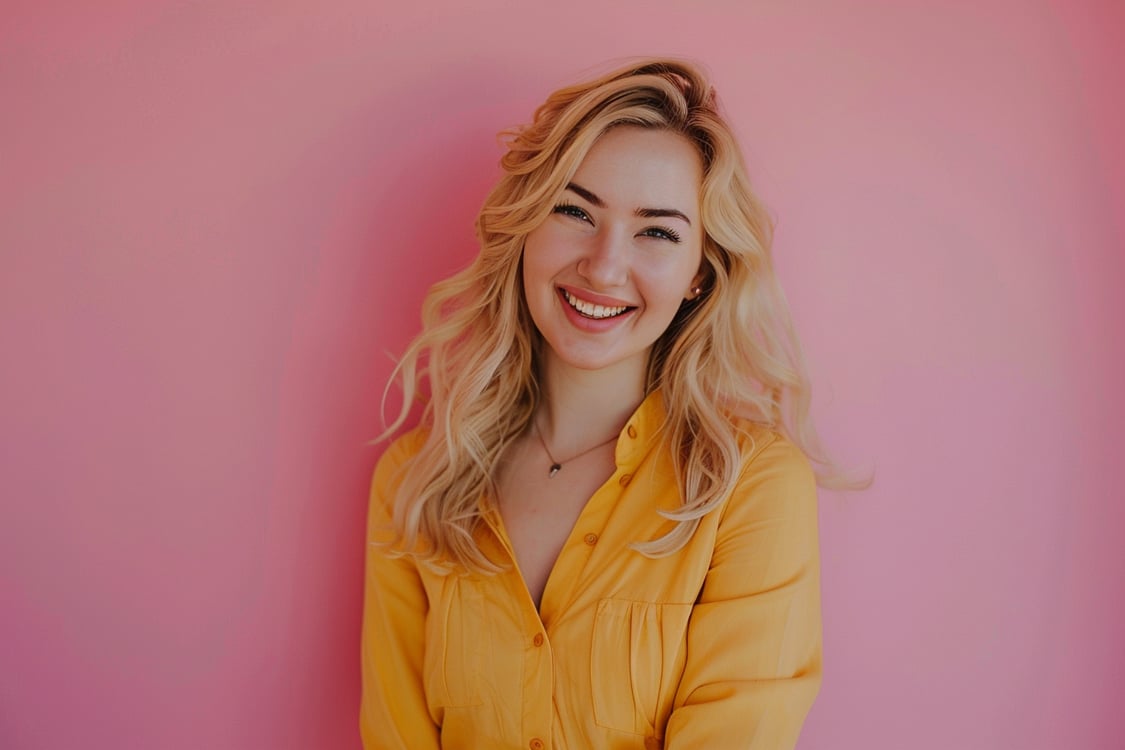 mulher loira de amarelo na parede rosa